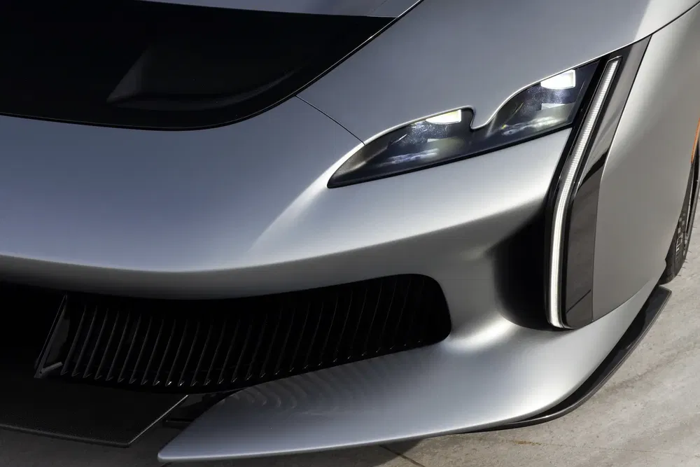 Détail d'une supercar électrique avec phares LED et design futuriste, finition argentée.