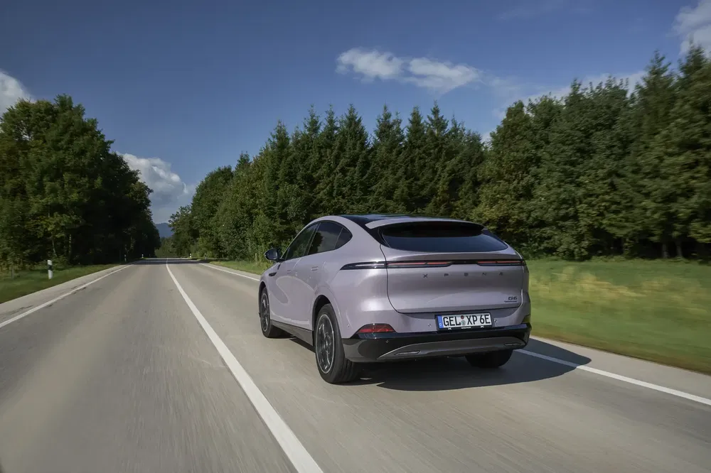 Voiture électrique XPeng G6 sur autoroute bordée d'arbres, arrière dynamique.