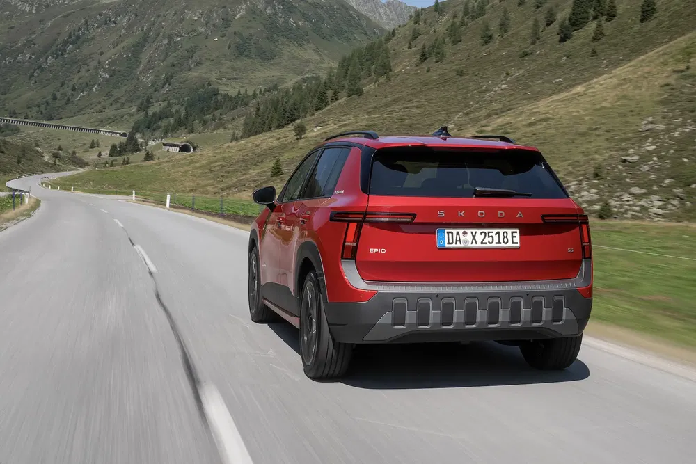 SUV Skoda Enyaq rouge sur route de montagne, montrant l'arrière élégant et moderne.