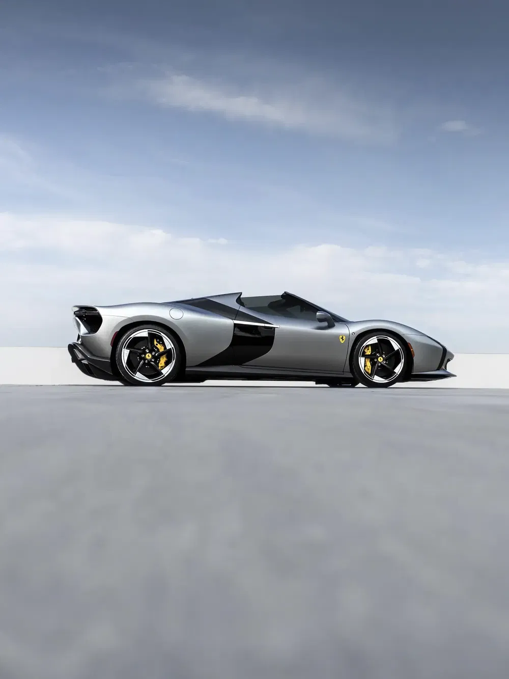 Ferrari SP48 Unica 2023, voiture de sport grise profilée sur fond de ciel bleu.