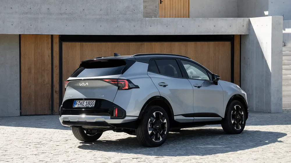 SUV Kia Sportage gris stationné devant un bâtiment moderne, design contemporain et élégant.