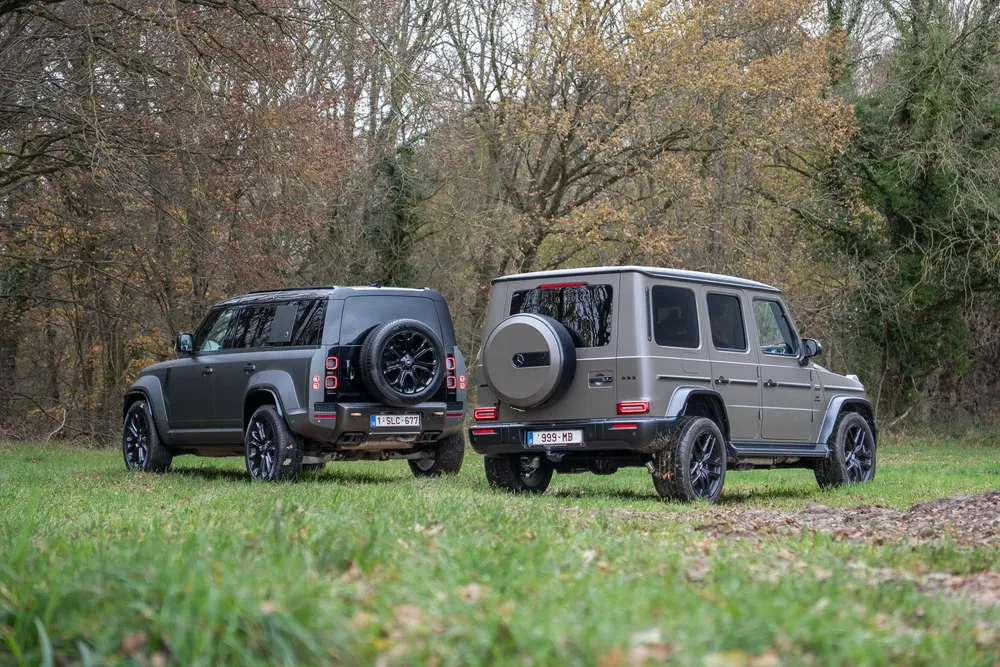 SUV Land Rover Defender et Mercedes Classe G sur gazon au milieu de la forêt.
