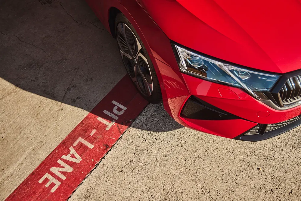 Voiture rouge Skoda dans la voie des stands éclairée par le soleil.