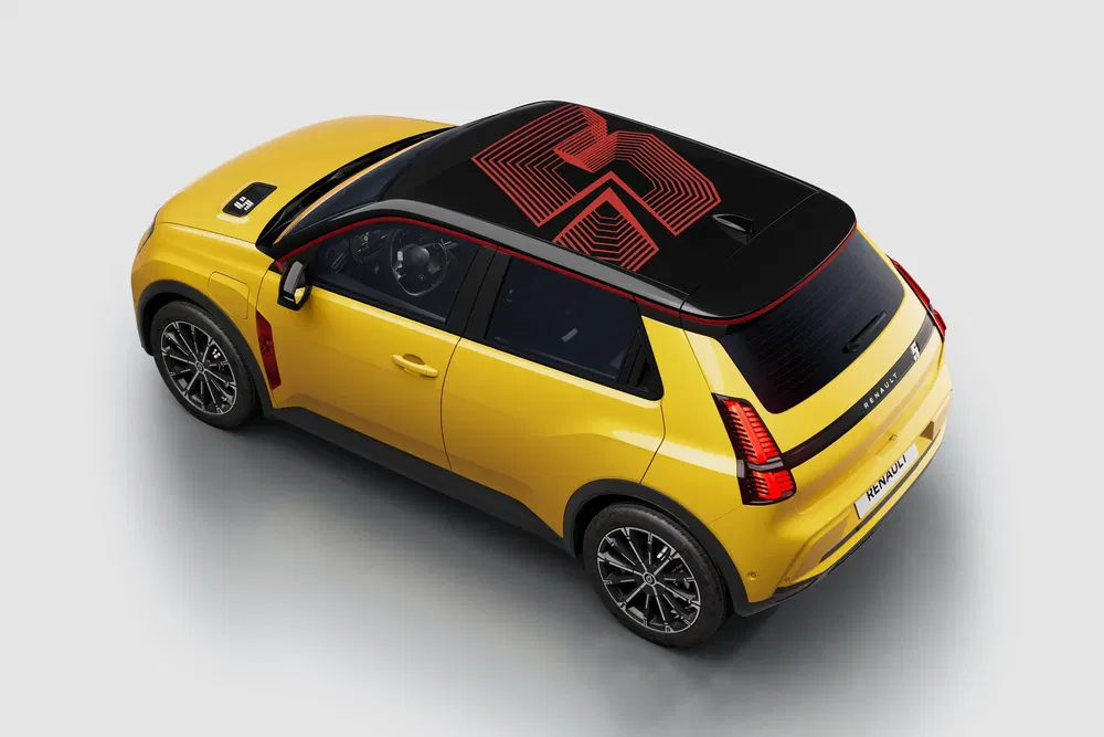 Renault 5 électrique jaune avec motif de toit noir et rouge, design moderne et compact.