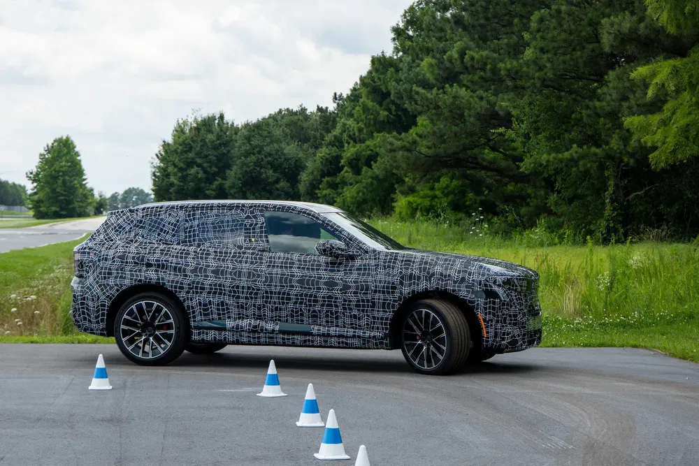 Verborgen BMW SUV op testcircuit met uitgelijnde verkeerskegels aan de voorkant.