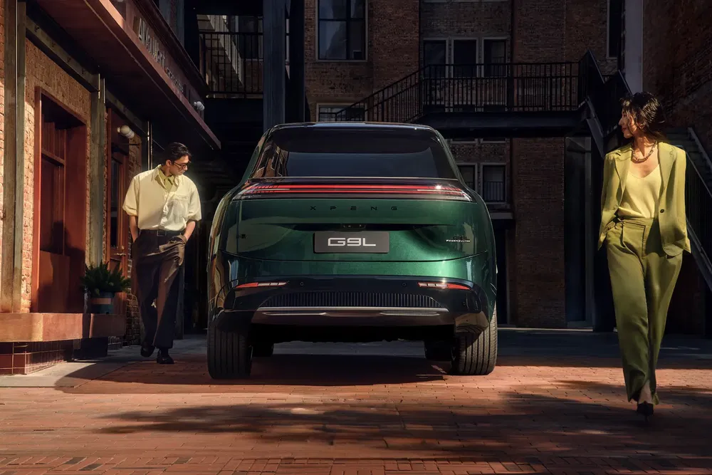 Voiture électrique XPeng G9L verte stationnée, avec deux personnes élégantes à proximité.