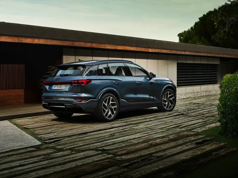 Blauwe elektrische Audi SUV geparkeerd voor een modern huis.