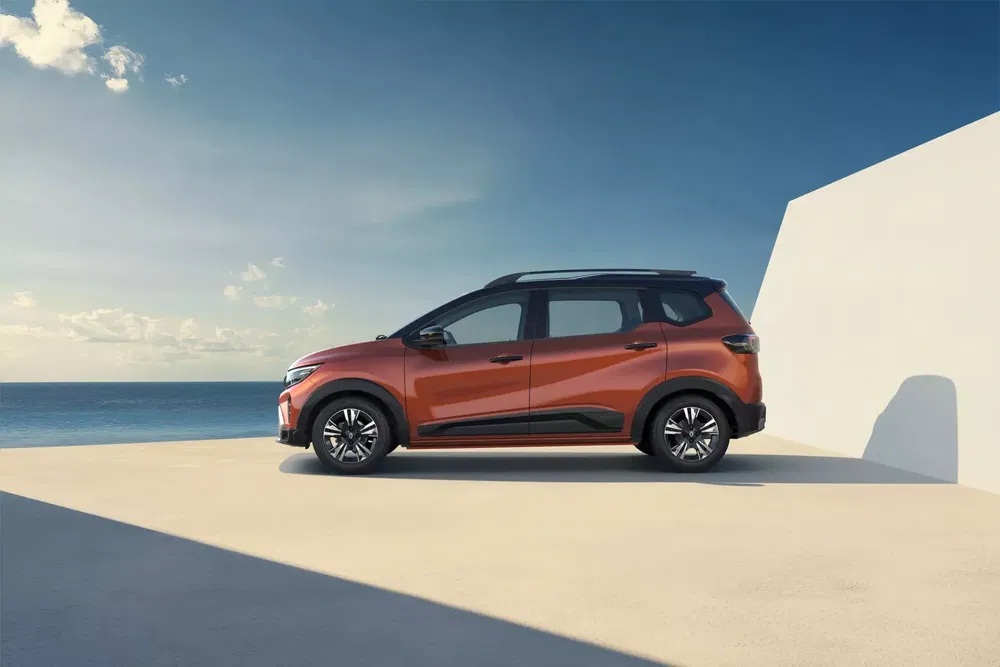 SUV Dacia Jogger orange au bord de la mer, sous un ciel bleu dégagé.
