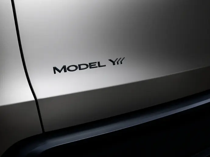 Insigne Tesla Model Y sur la carrosserie gris métallique d'un véhicule électrique.