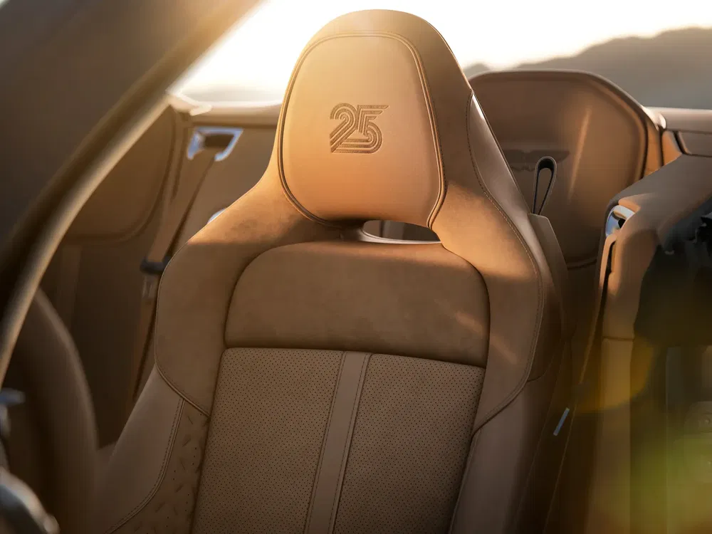 Intérieur de voiture Porsche avec siège en cuir beige et logo 25e anniversaire gravé.
