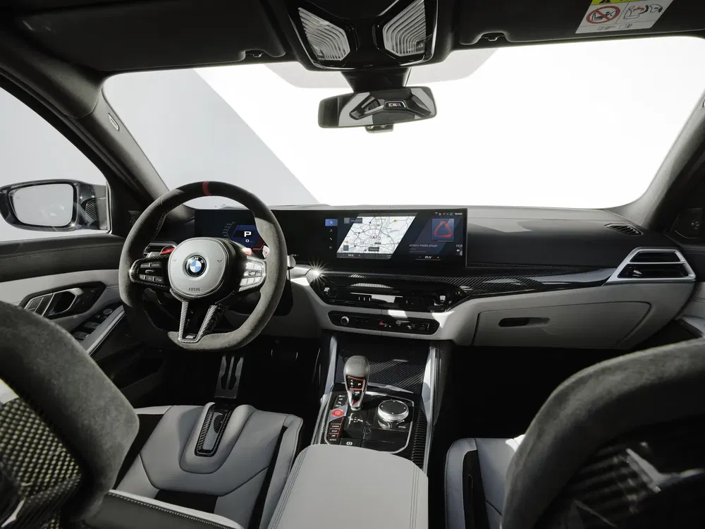 Moderne interieur van de BMW M3 met lederen stuur en digitaal display.