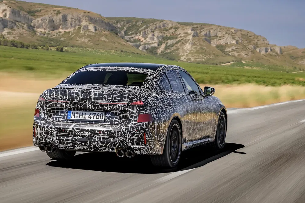 Prototype BMW série camouflée sur route montagneuse, test haute vitesse.