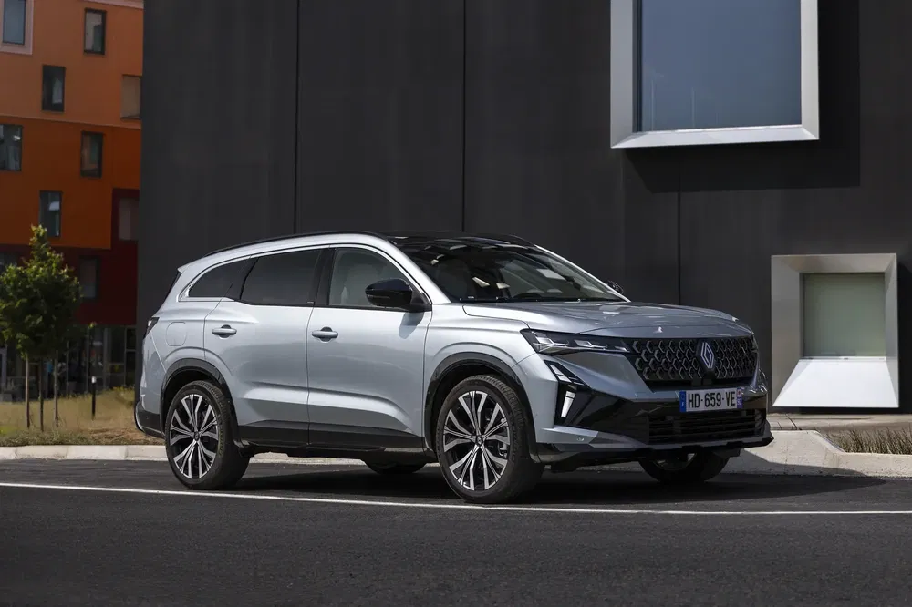 Renault Espace 2023 SUV argenté garé devant un bâtiment moderne, quartier urbain.