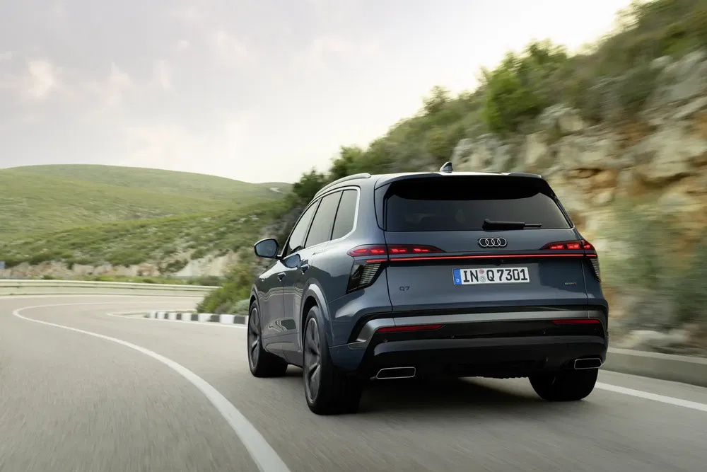 Audi Q7 sur route sinueuse dans un cadre naturel verdoyant.