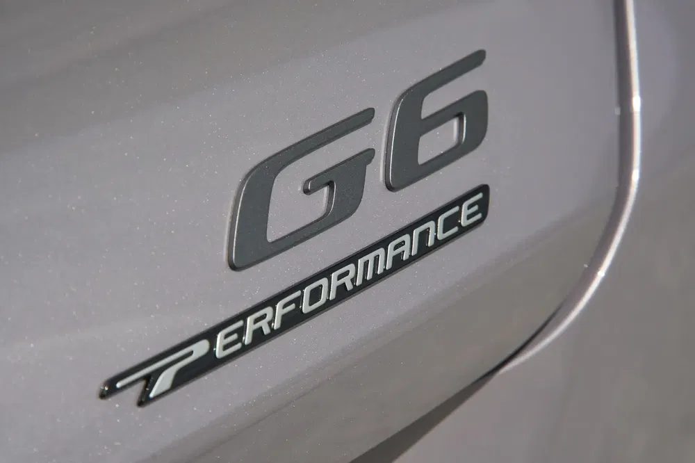 Badge G6 Performance sur carrosserie argentée de voiture, accentuant puissance et style.