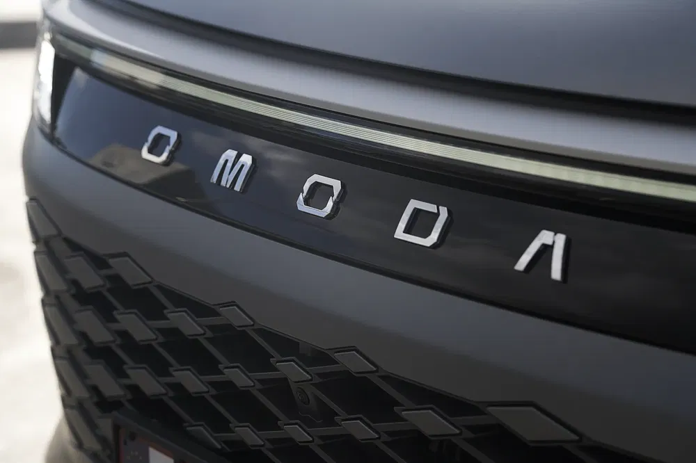 Close-up van het Omoda auto-embleem op de voorgrille, met modern design.