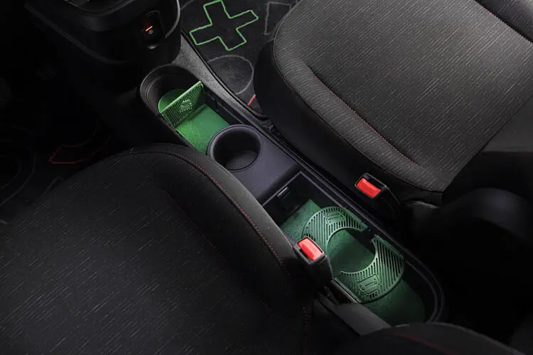 Intérieur d'une voiture avec support de bouteille entre les sièges avant et tapis vert.