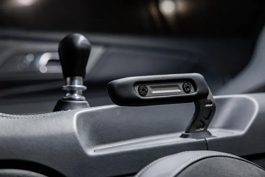 Poignée de frein à main innovante dans une voiture moderne avec levier de vitesses visible.