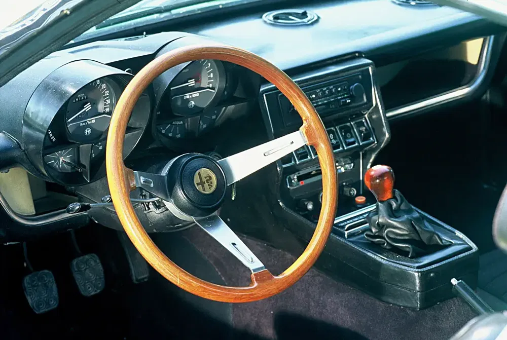 Intérieur classique Alfa Romeo avec volant en bois et tableau de bord vintage.