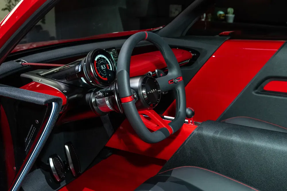 Futuristisch Mazda-interieur met digitale dashboard en stijlvolle rode afwerkingen.