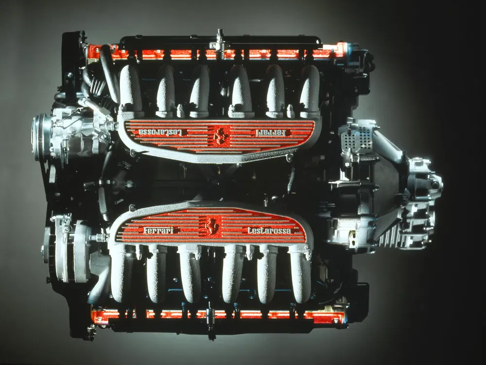 Iconische Ferrari Testarossa motor met rode kleppendeksels en steigerend paard logo.
