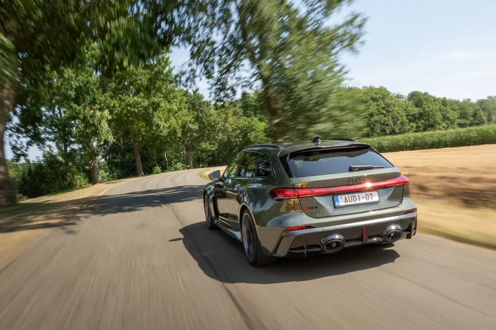 Audi RS6 stationwagen krachtig op landweg, omgeven door zomerweelde.