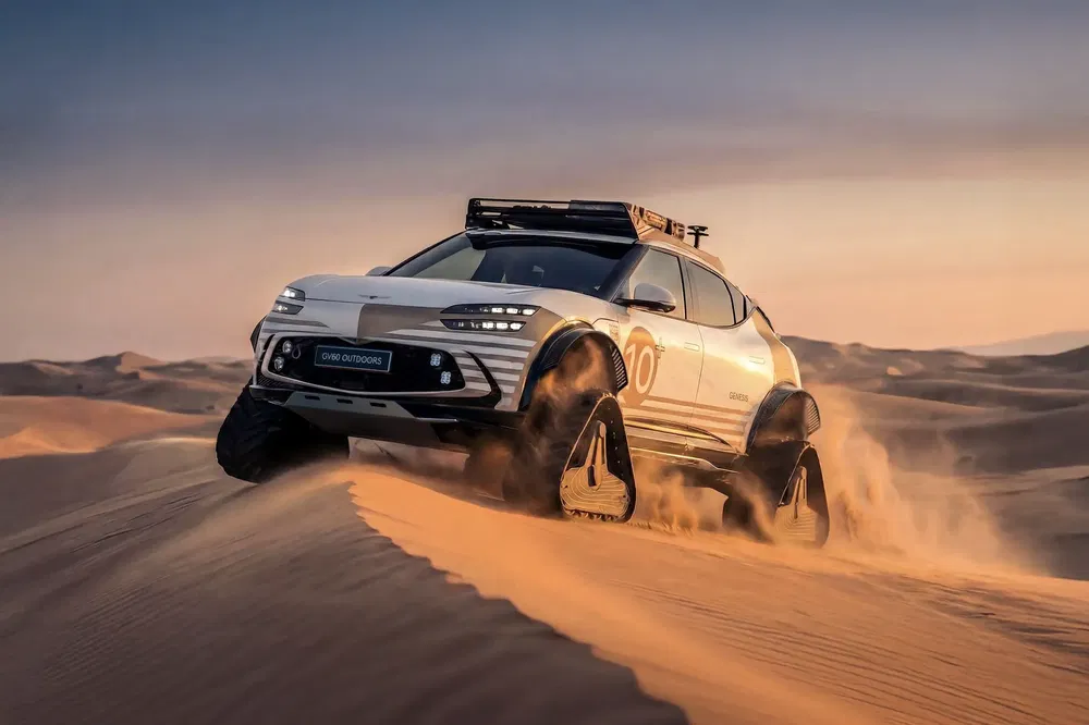 SUV équipé de chenilles traversant le désert, créant des nuages de sable spectaculaire.
