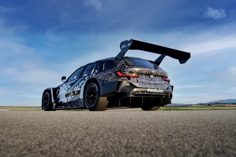 BMW M3 raceauto met grote achterspoiler op openluchtbaan.