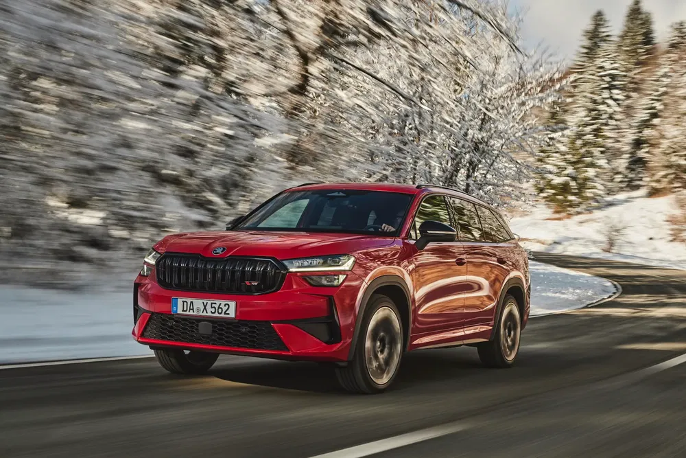 Škoda Kodiaq rouge roulant sur route enneigée en montagne.