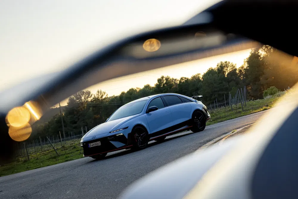 Hyundai Ioniq 6 électrique sur route de campagne au coucher du soleil, design moderne et élégant.