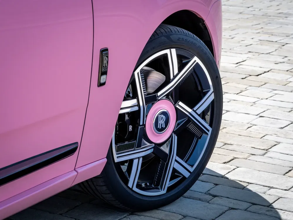 Jante de Rolls-Royce rose avec logo distinctif sur fond de pavés.