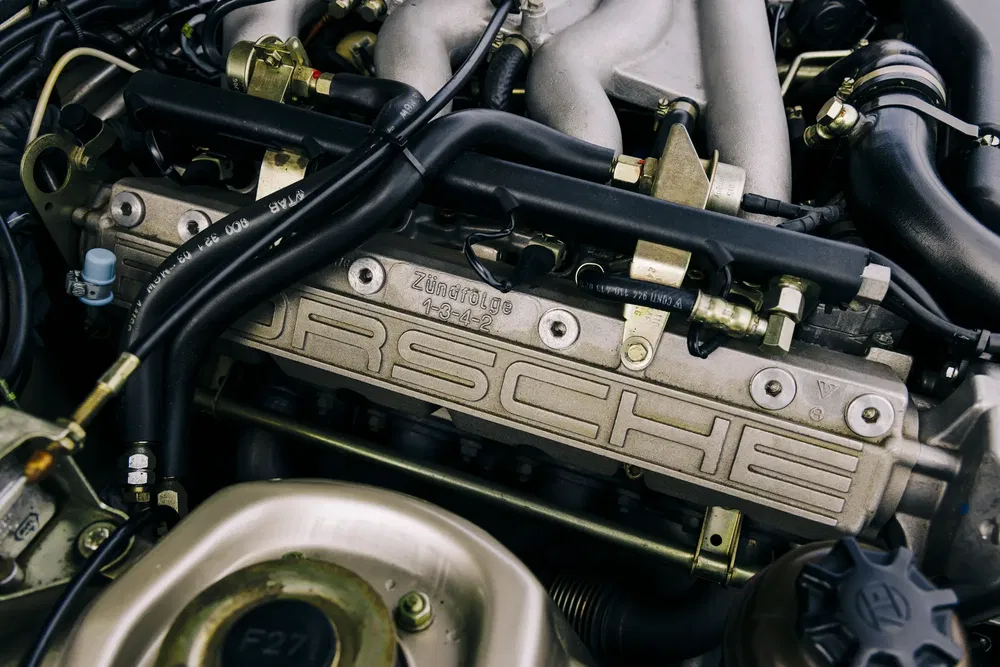 Moteur Porsche détaillé montrant le logo distinctif et le système d'allumage complexe.