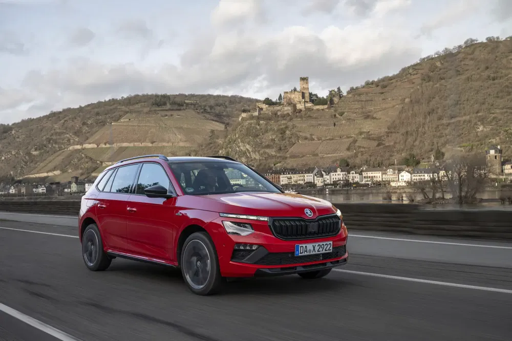 Škoda Kamiq rouge roulant sur route avec paysage montagneux en arrière-plan.