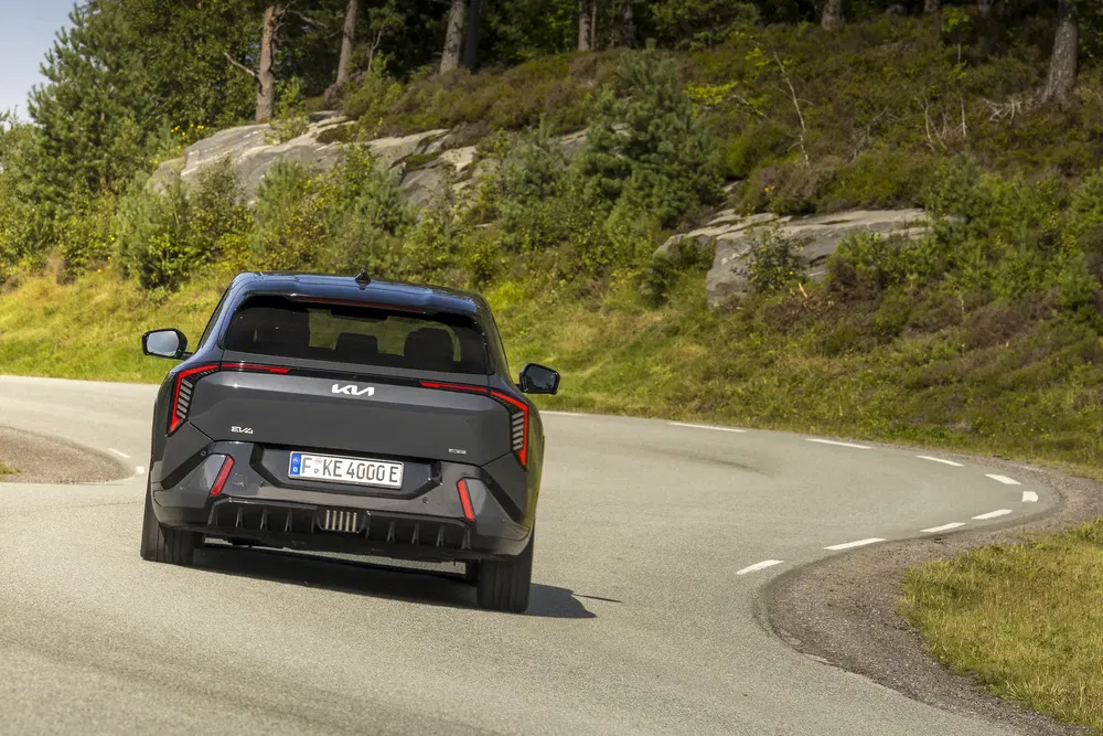 Kia EV6 GT noir sur route sinueuse entourée de forêt luxuriante.