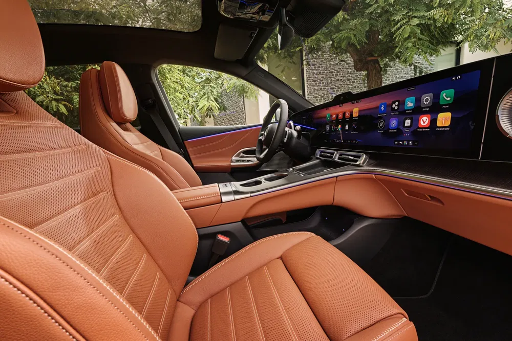Auto-interieur met bruine lederen stoelen en een modern digitaal dashboard.