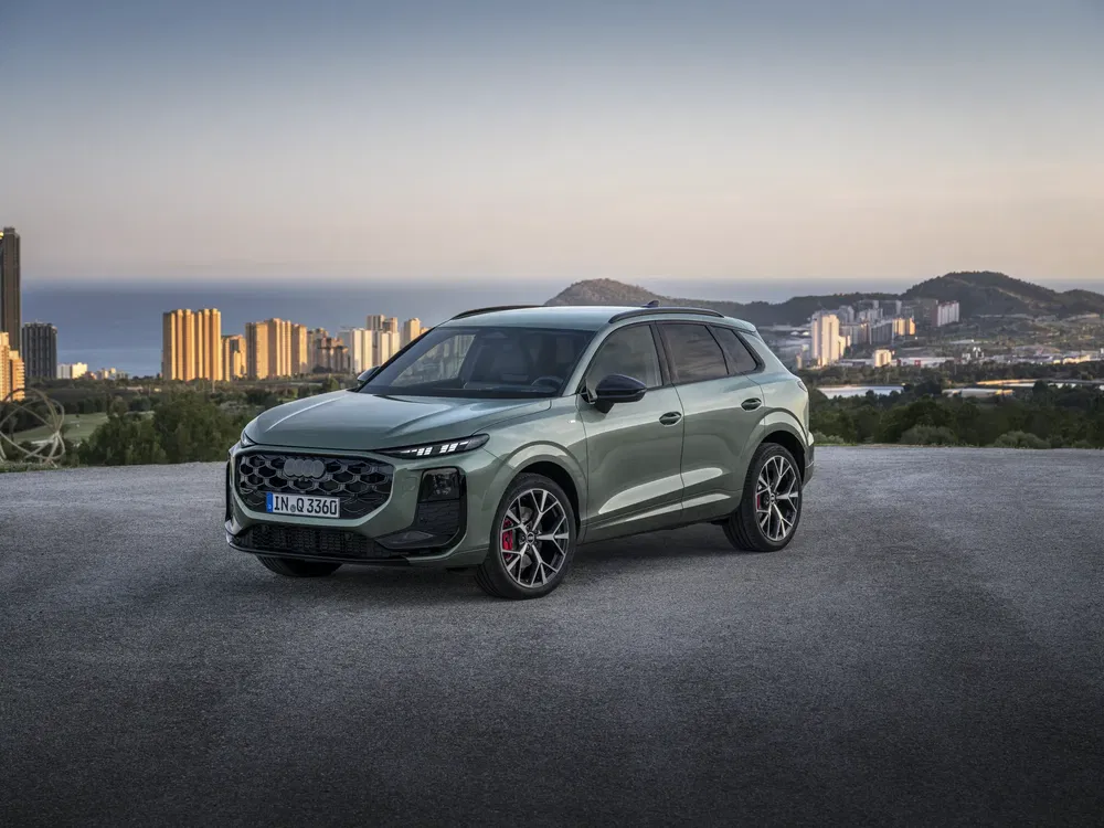 Audi SUV geparkeerd met stadsuitzicht op de achtergrond, schemerverlichting.
