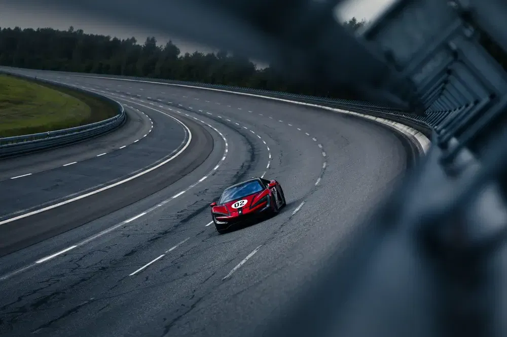 {"fr":"Voiture de course rouge Ferrari sur piste de circuit incurvée, entourée de verdure.","nl":"Rode raceauto Ferrari op een bochtig circuit, omringd door groen landschap."}