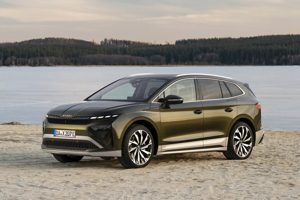 Škoda Enyaq iV électrique sur une plage avec un lac en arrière-plan, design moderne et élégant.