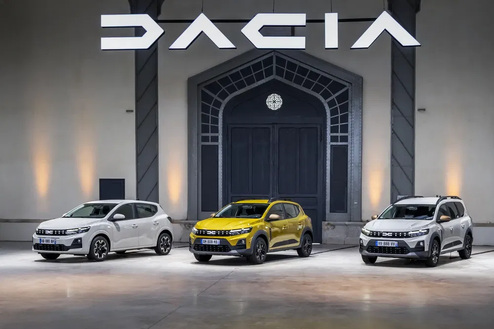 Trois modèles de voitures Dacia exposés dans un showroom spacieux.