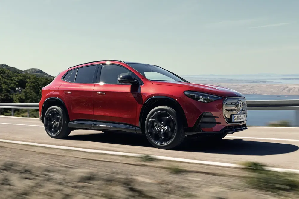 Rode Mercedes-Benz GLA rijdt op een schilderachtige kustweg bij daglicht.