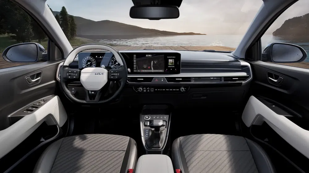 Interieur van Kia SUV, stuur en hoogtechnologisch dashboard met uitzicht op zee.