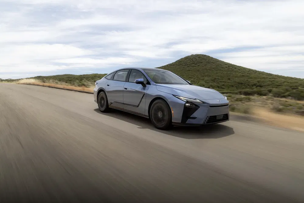 Toyota Mirai 2023 bleu roulant sur une route déserte avec colline en arrière-plan.