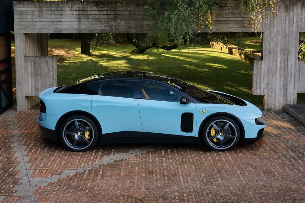 Ferrari au design moderne garée devant un mur, sur sol en brique, entourée de verdure.
