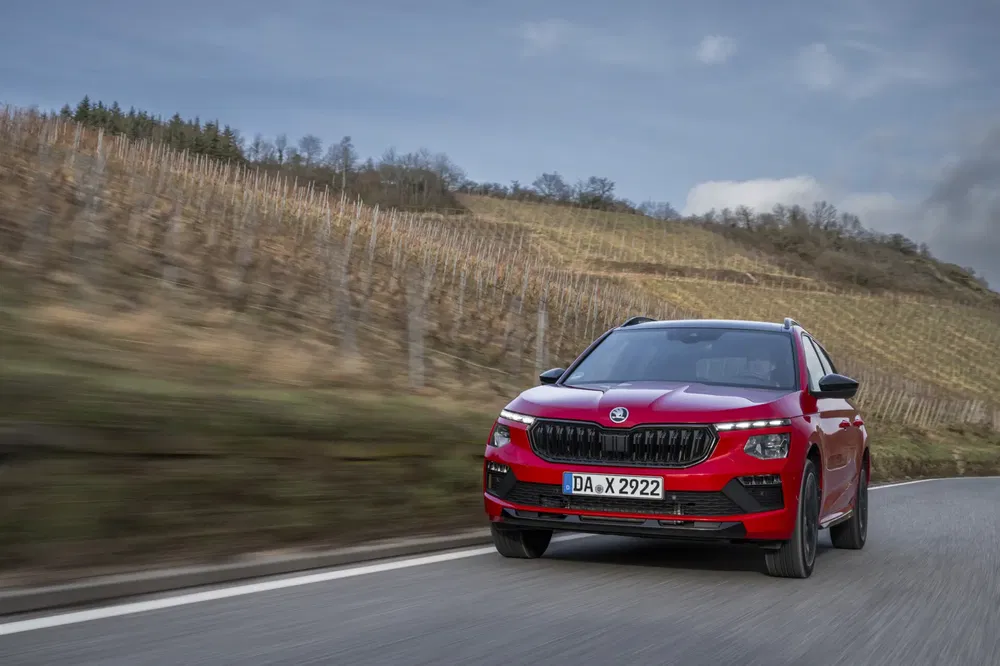 Škoda Kamiq rouge roulant sur une route de campagne vallonnée.