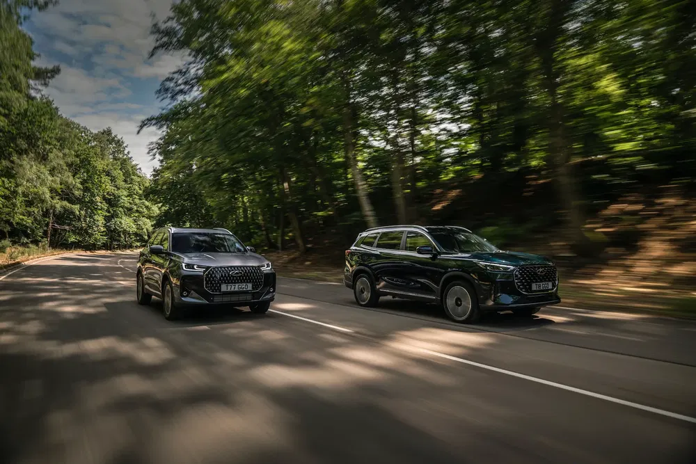 SUV Haval modernes roulant sur une route bordée d'arbres sous un ciel clair.
