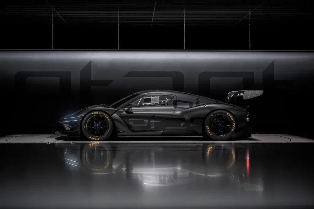 Voiture de course haute performance noire, design aérodynamique, sur fond de garage moderne.