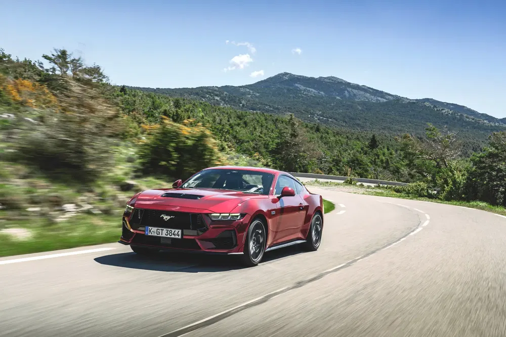 {"fr":"Ford Mustang rouge sur route sinueuse avec paysage montagneux en arrière-plan.","nl":"Rode Ford Mustang op bochtige weg met berglandschap op achtergrond."}