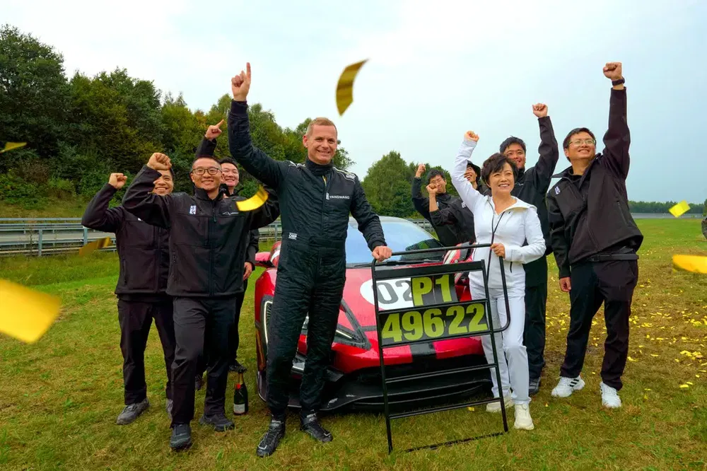 Feestelijke overwinning met een rode supercar en enthousiast team op een racecircuit.