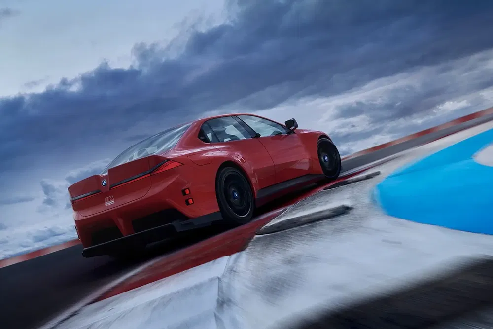 BMW Concept Neue Klasse rouge sur circuit sous ciel orageux.