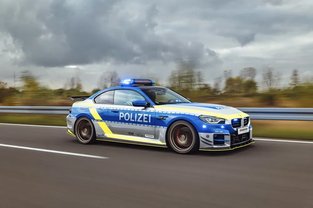 BMW Polizei en action sur autoroute nuageuse, équipée de gyrophares bleus.